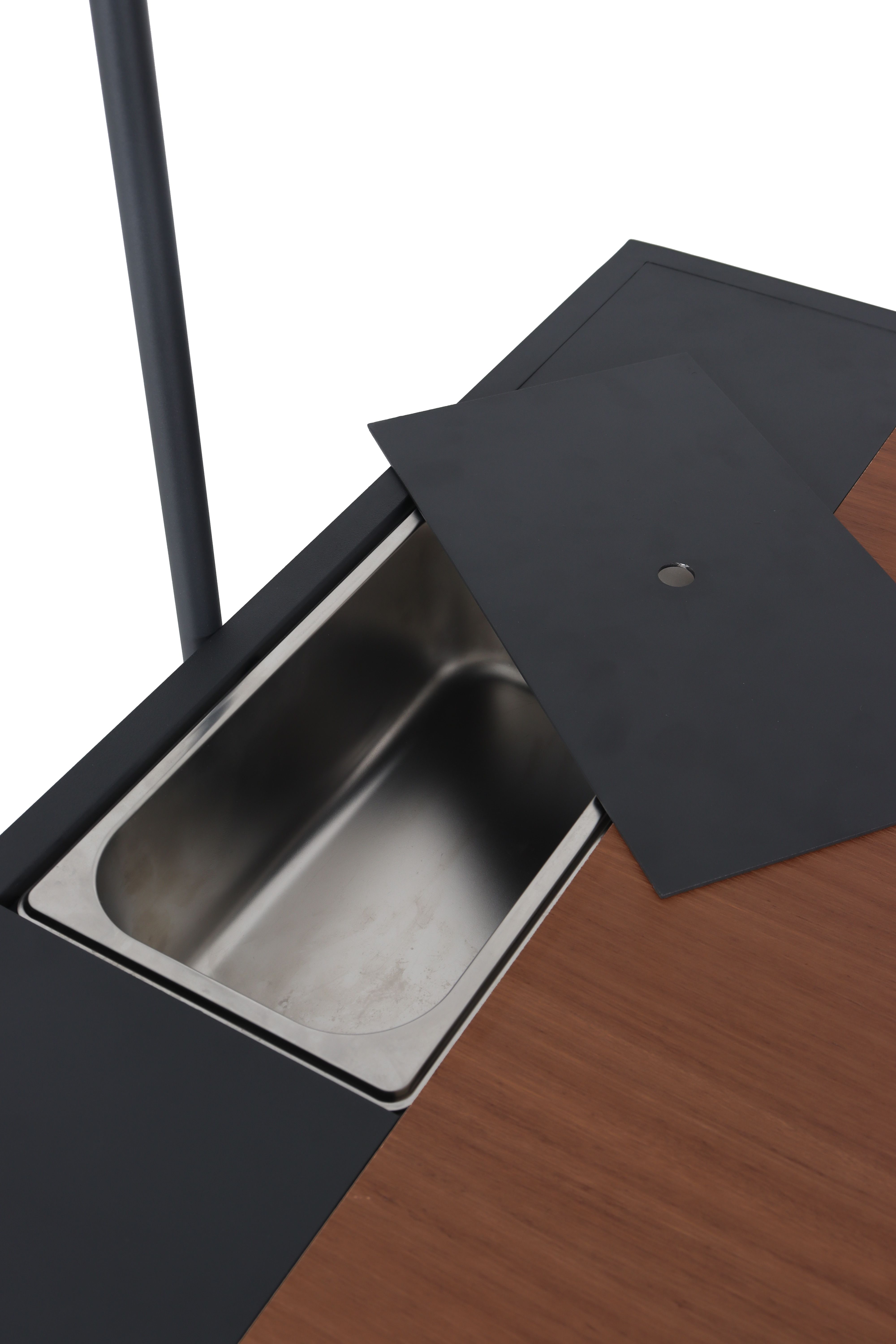 Offene Edelstahlwanne in einem Tisch mit herausnehmbarer schwarzer Abdeckung auf Holzplatte.