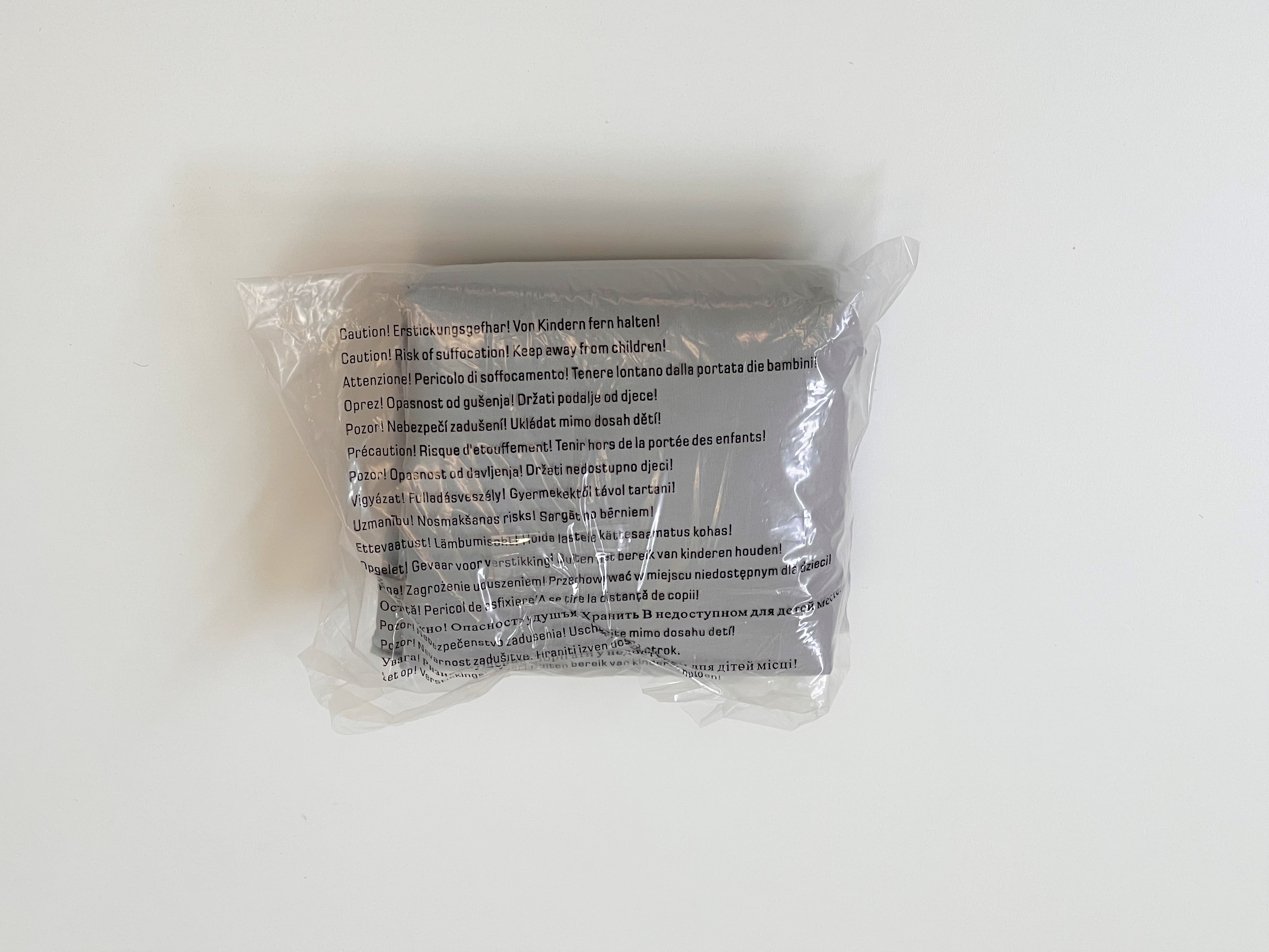 Plastikverpackung mit Hinweis auf Erstickungsgefahr, von Kindern fernhalten. Text in mehreren Sprachen.