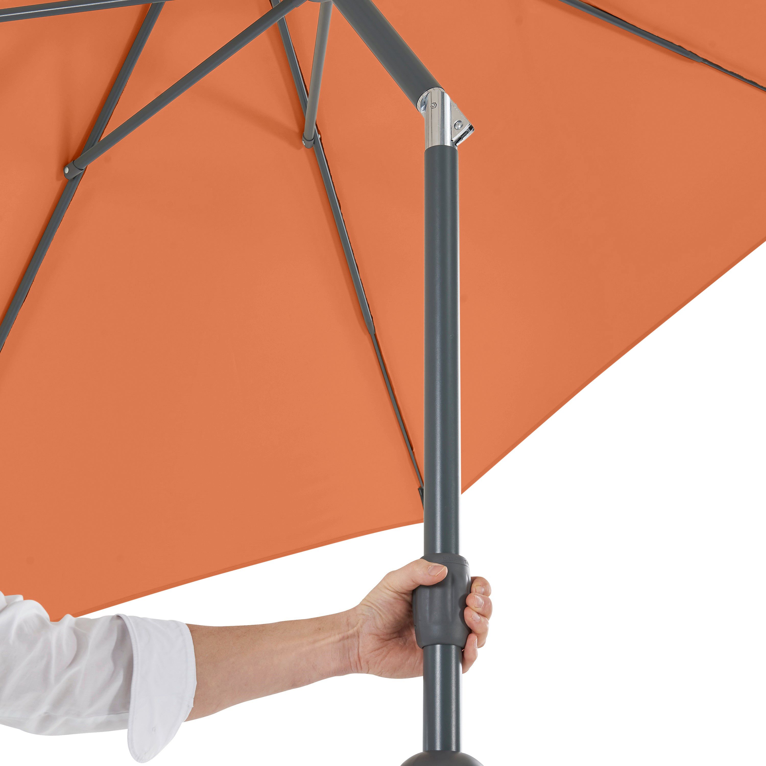 Hand hält das Rohr eines orangefarbenen Sonnenschirms.