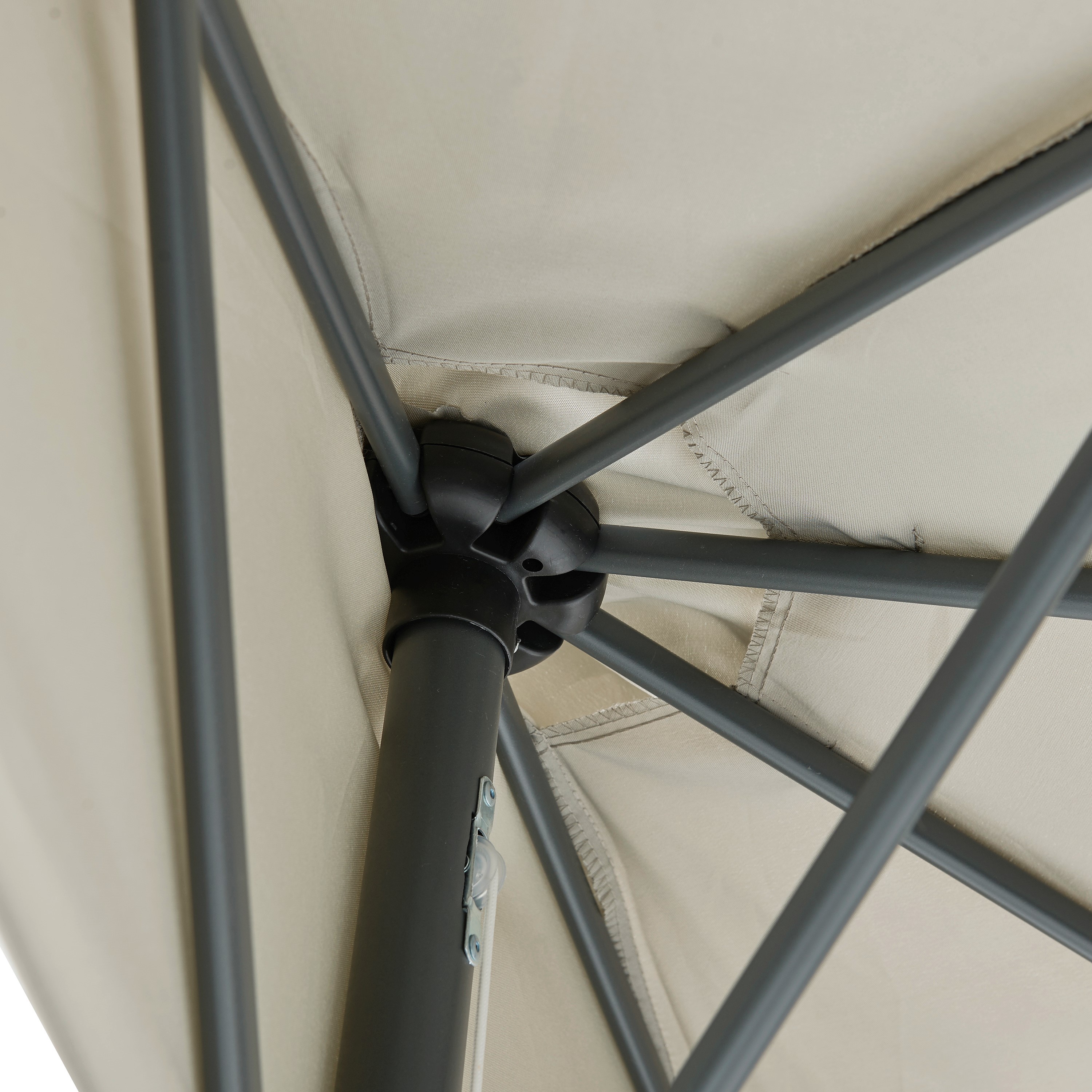 Nahaufnahme der Stahlstreben und des Verbindungsstücks eines geöffneten Sonnenschirms mit hellem Stoff.