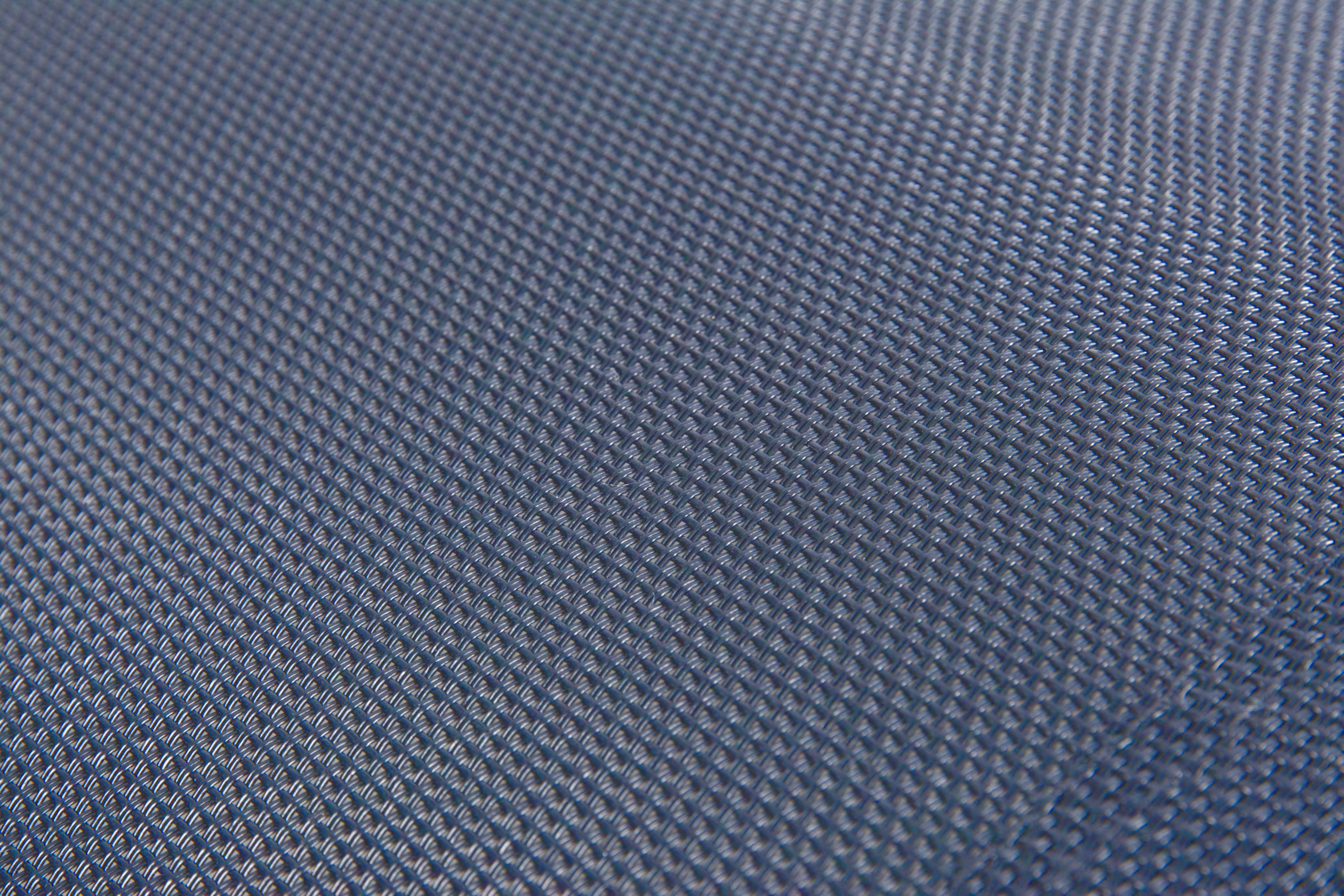 Nahaufnahme eines blauen, texturierten Gewebes mit gleichmäßigem Muster. Diagonal verlaufende Linien.