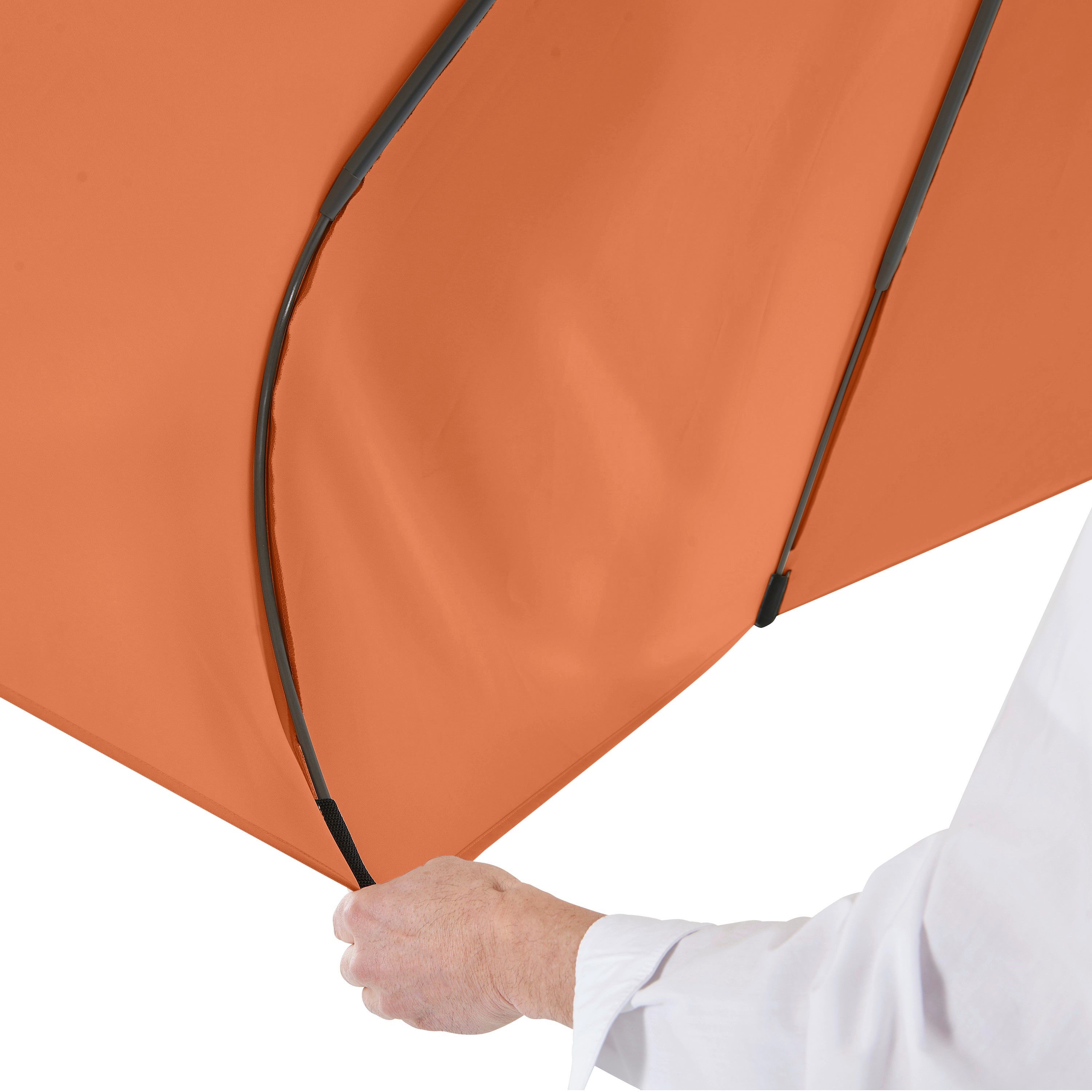 Hand hält die Strebe eines orangefarbenen Regenschirms. Person trägt weißes Hemd.